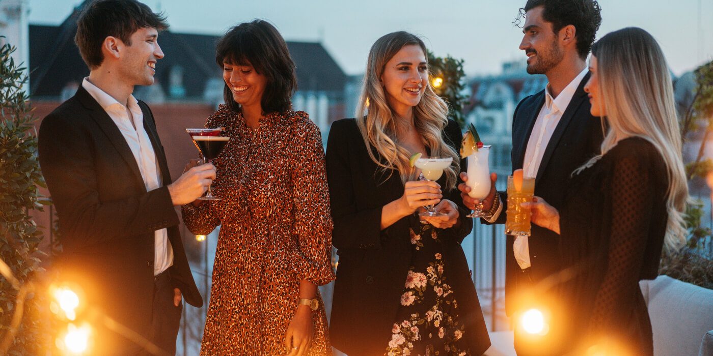Gruppe junger Leute auf Dachterrasse mit diversen Speakeasy Cocktails