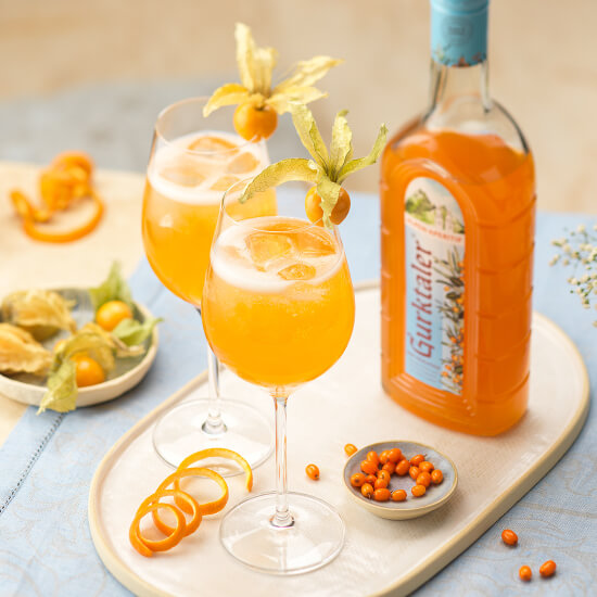 Gurktaler Alpen-Aperitif als Spritz auf gedecktem Tisch mit zwei Cocktailgläsern