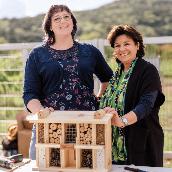Zwei Frauen präsentieren einen selbstgebauten Bienenstock