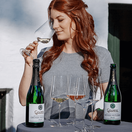Eine Frau riecht an einem Weinglas in der sich Wein der Marke Goldeck befindet.
