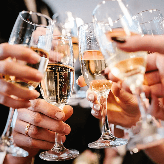 Nahaufnahme einer Gruppe Leute die Sektgläser zusammenstößt