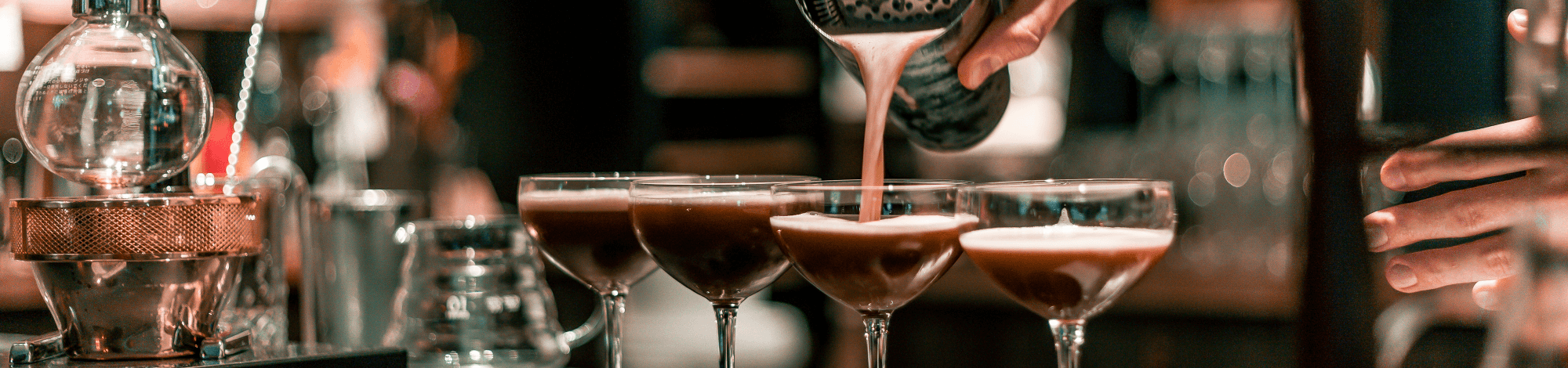 Barkeeper schüttet den Cocktails aus dem Mixer in die Gläser