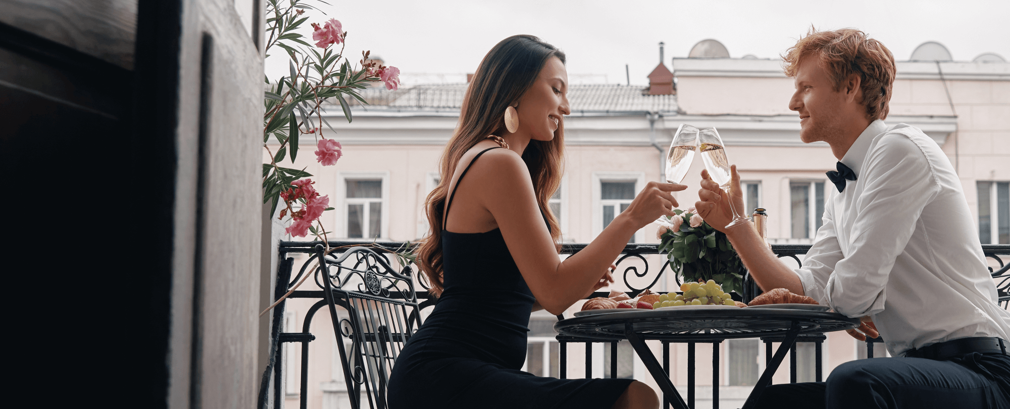 Ein Paar sitzt schön gekleidet auf der Terrasse, isst und trinkt Sekt.