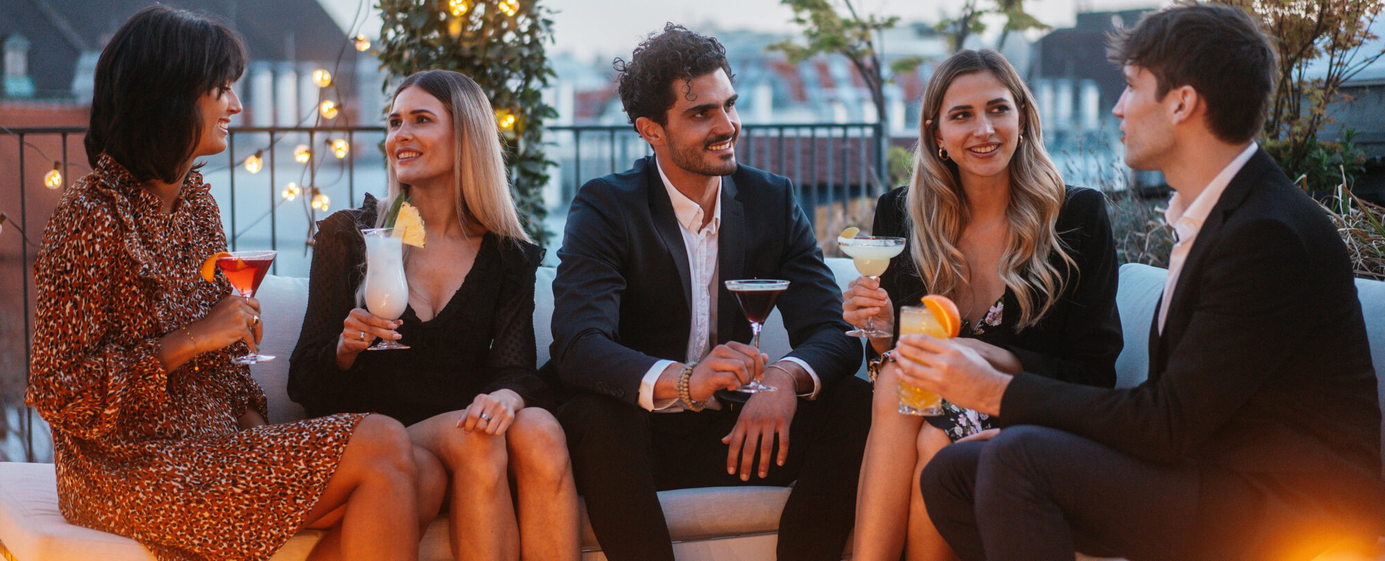 Eine Gruppe Erwachsener sitzt draußen zusammen und trinkt Cocktails 